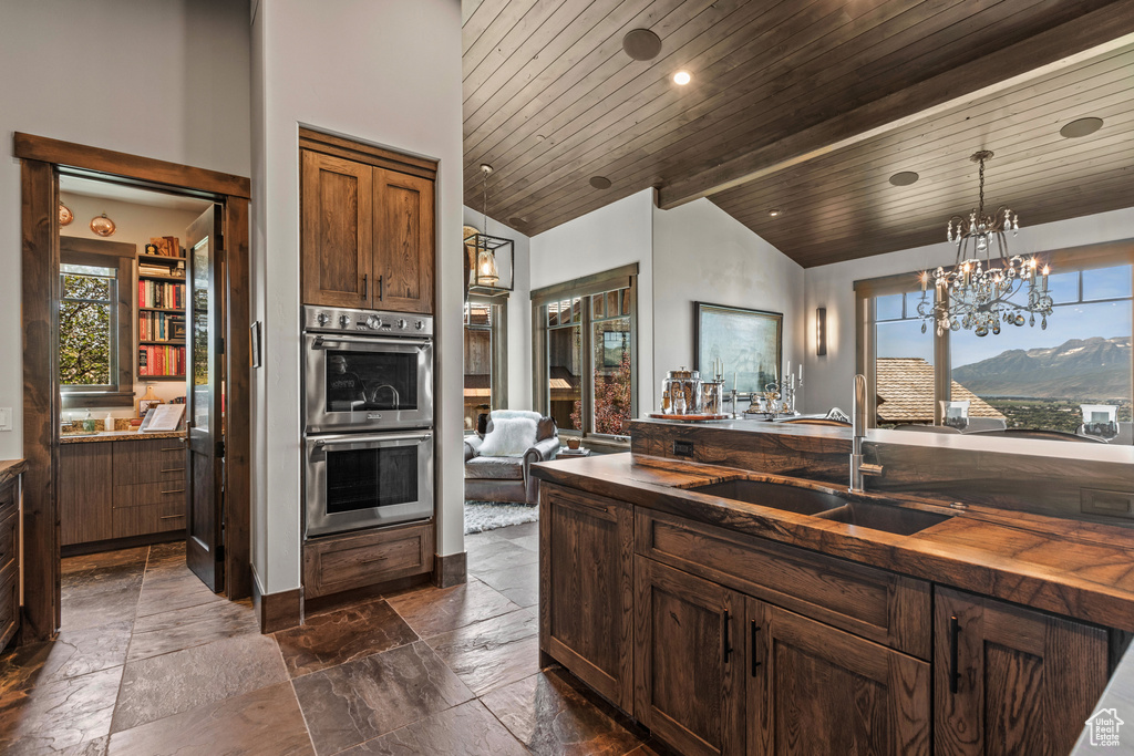 Kitchen with vaulted ceiling with beams, double oven, sink, a mountain view, and wood ceiling