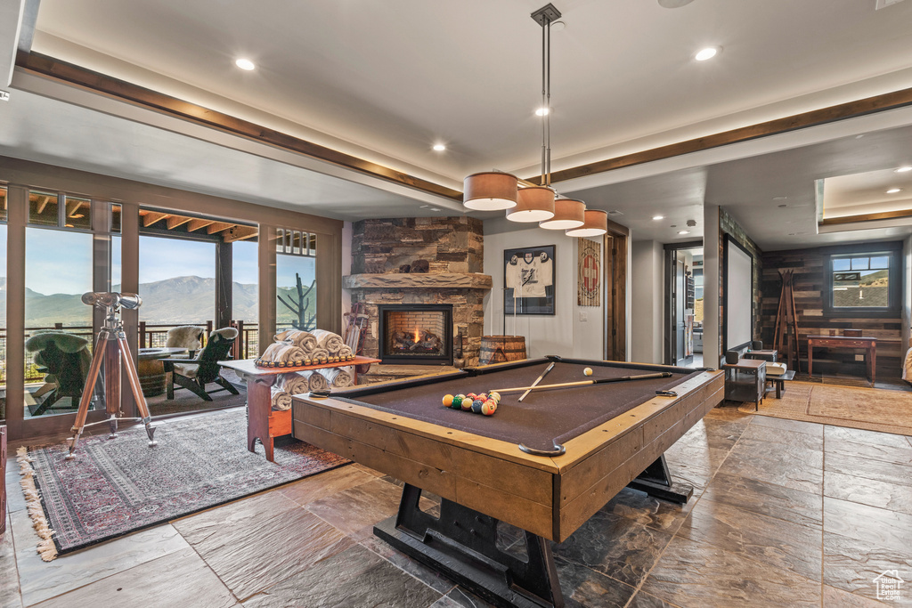 Rec room featuring a raised ceiling, a stone fireplace, billiards, a mountain view, and dark tile floors