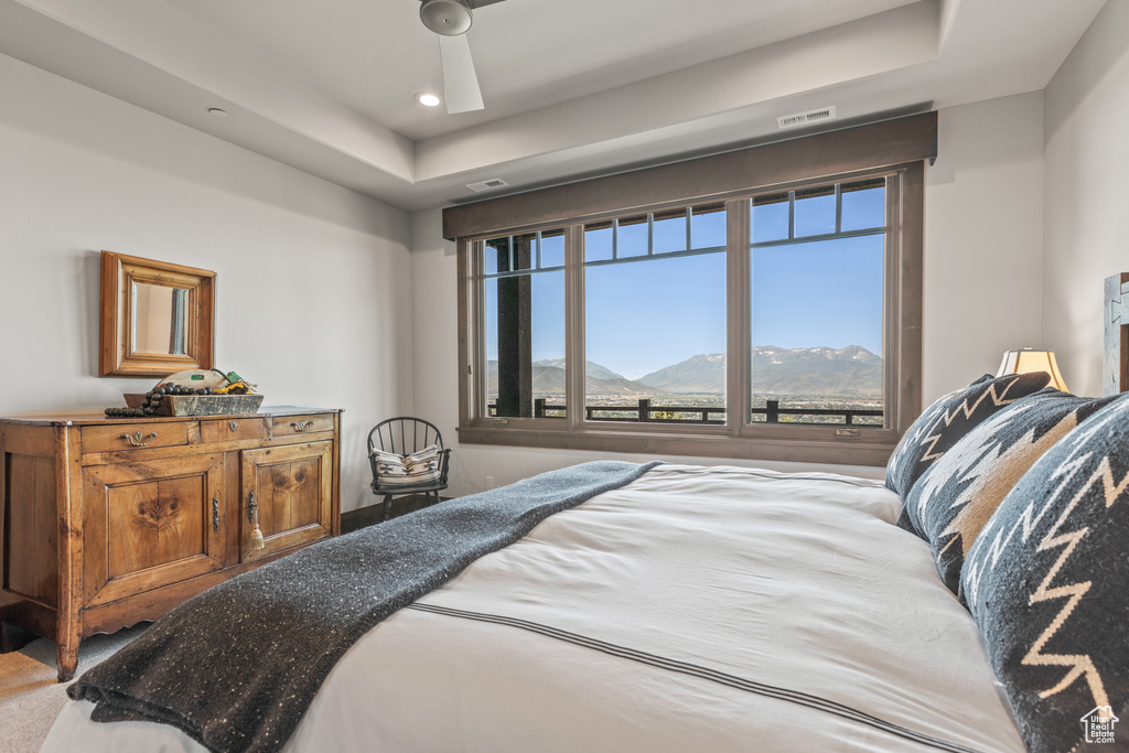 Bedroom with a raised ceiling, a mountain view, carpet, and ceiling fan