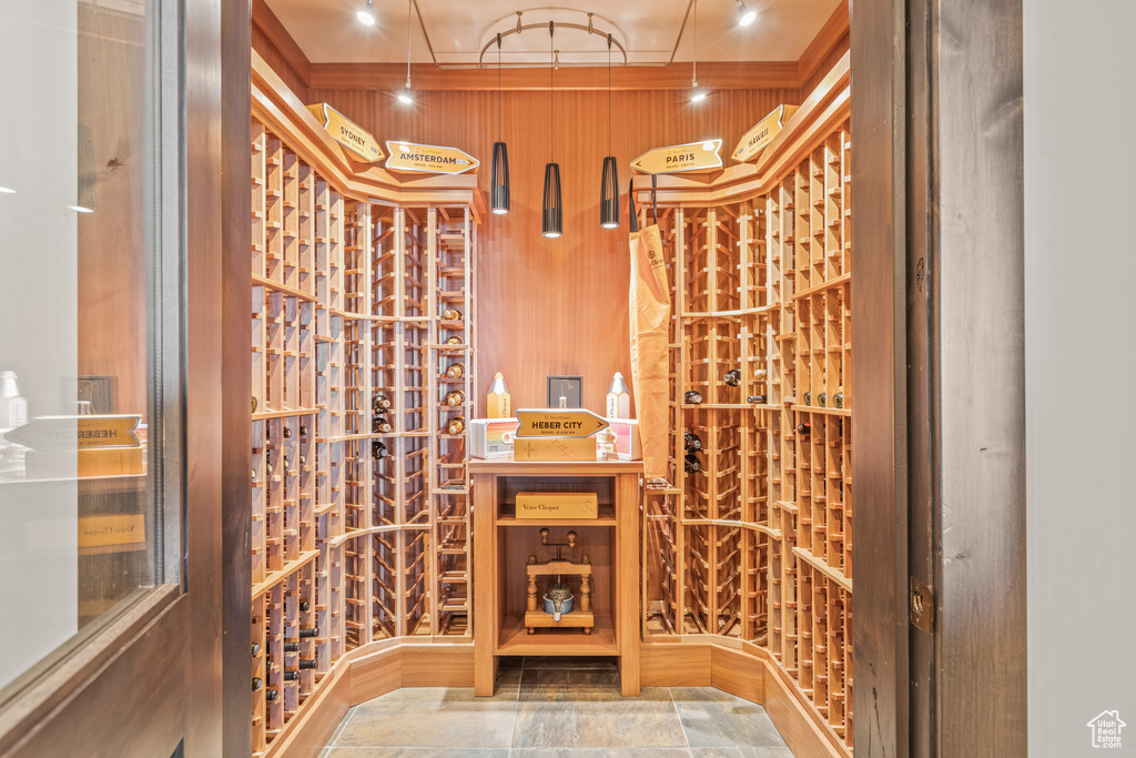 Wine cellar featuring rail lighting and dark tile floors