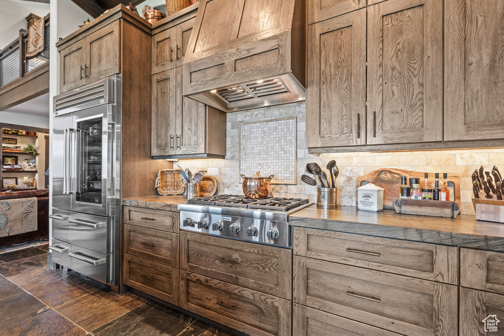 Kitchen featuring multiple ovens, tasteful backsplash, custom range hood, and stainless steel gas stovetop