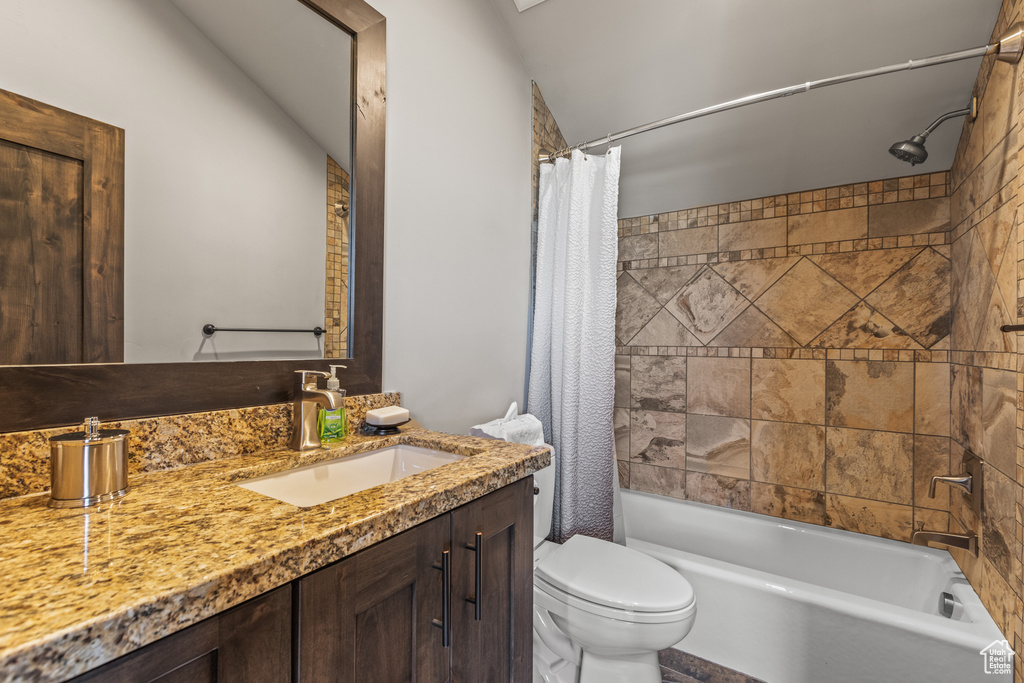 Full bathroom featuring vanity, vaulted ceiling, toilet, and shower / tub combo with curtain