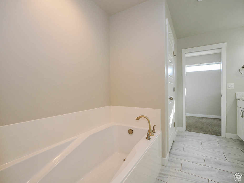 Bathroom featuring vanity, tiled bath, and tile flooring