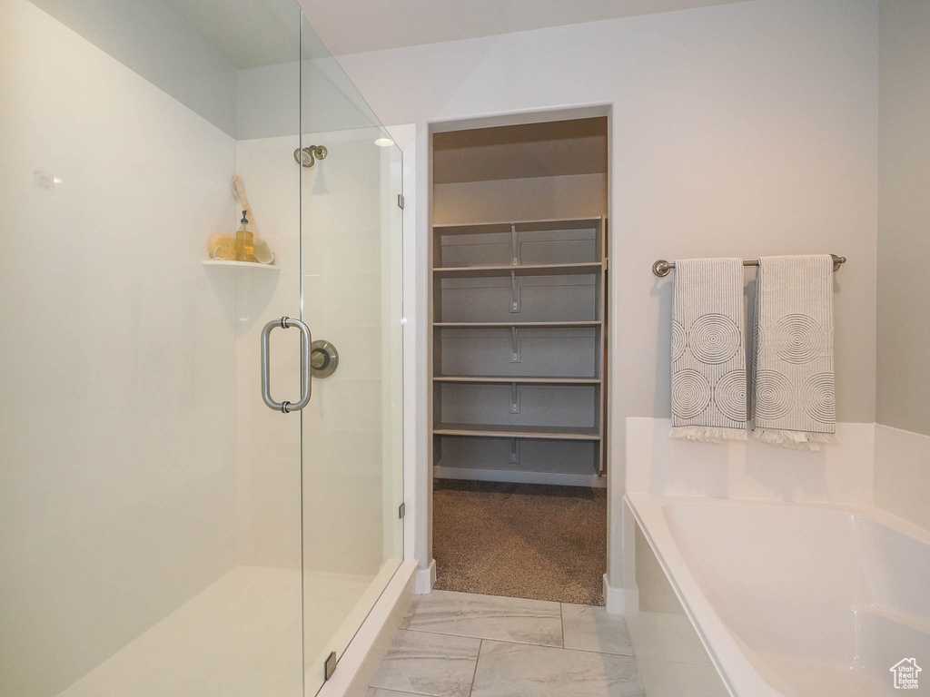 Bathroom featuring shower with separate bathtub and tile floors