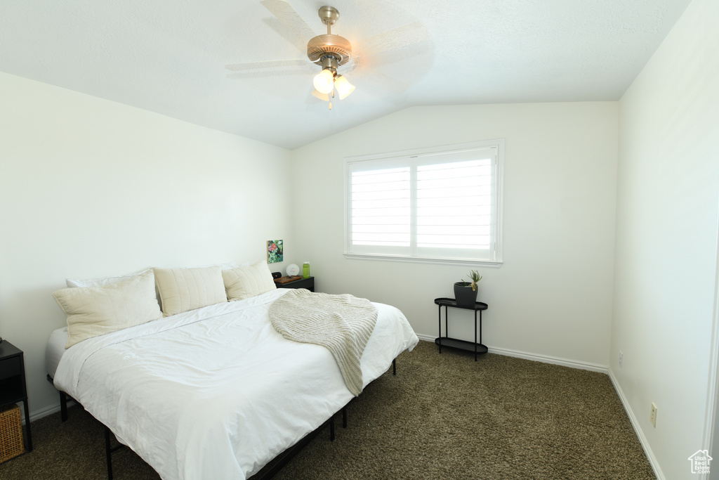 Bedroom featuring vaulted ceiling, dark carpet, and ceiling fan