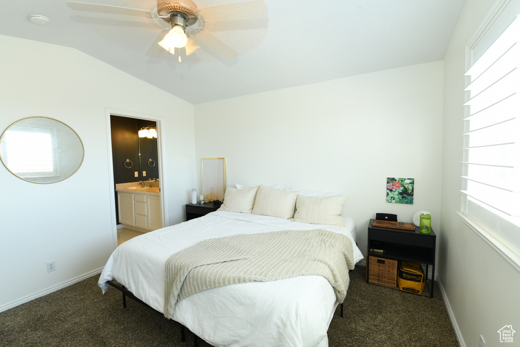 Bedroom featuring lofted ceiling, ensuite bath, dark colored carpet, and ceiling fan