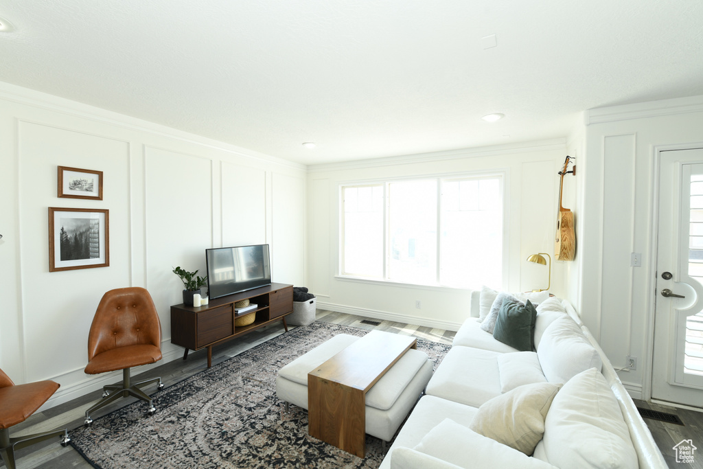 Living room featuring dark hardwood / wood-style floors, ornamental molding, and plenty of natural light