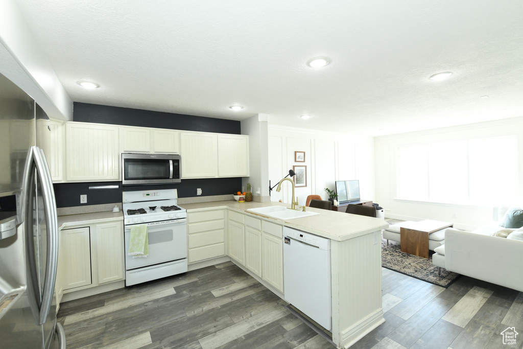 Kitchen with sink, kitchen peninsula, dark hardwood / wood-style flooring, and stainless steel appliances