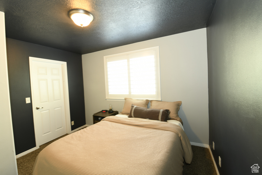 Bedroom featuring dark colored carpet and a textured ceiling
