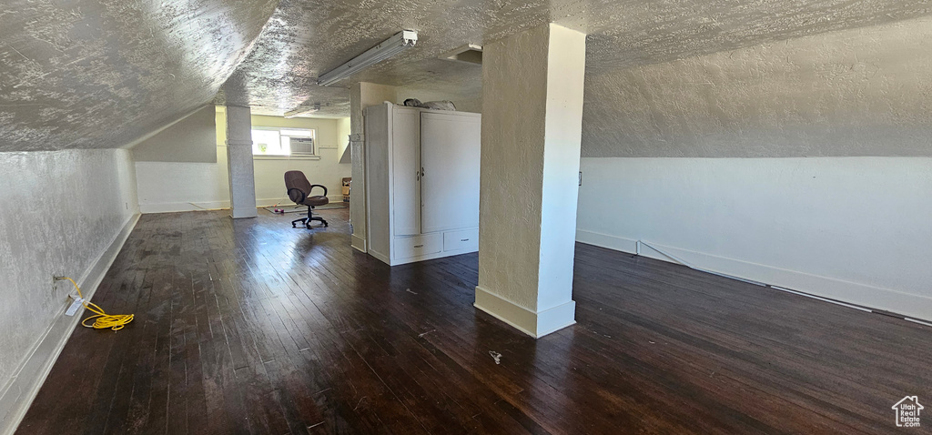 Additional living space with a textured ceiling, dark hardwood / wood-style flooring, and vaulted ceiling