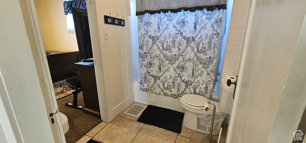 Full bathroom with vanity, toilet, shower / tub combo with curtain, and tile floors