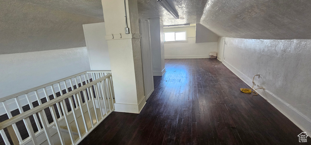 Bonus room with dark hardwood / wood-style flooring, a textured ceiling, and lofted ceiling