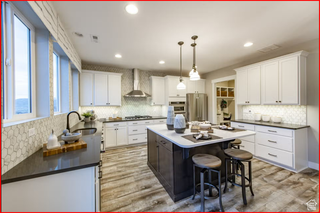Kitchen with a kitchen island, tasteful backsplash, wall chimney range hood, and appliances with stainless steel finishes