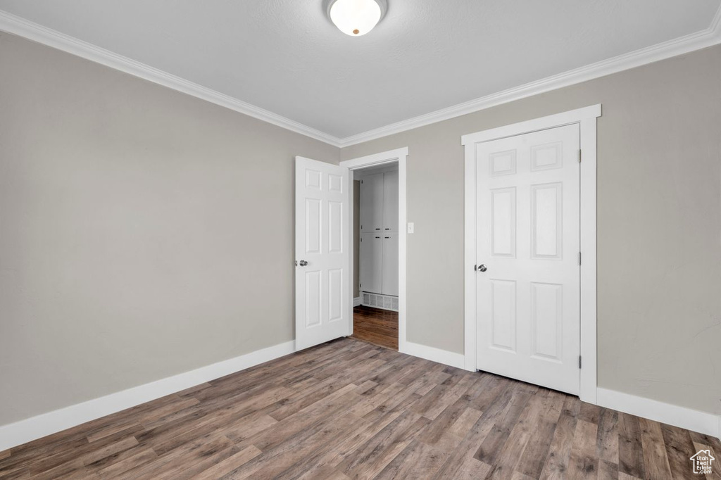 Unfurnished bedroom featuring dark hardwood / wood-style flooring and crown molding