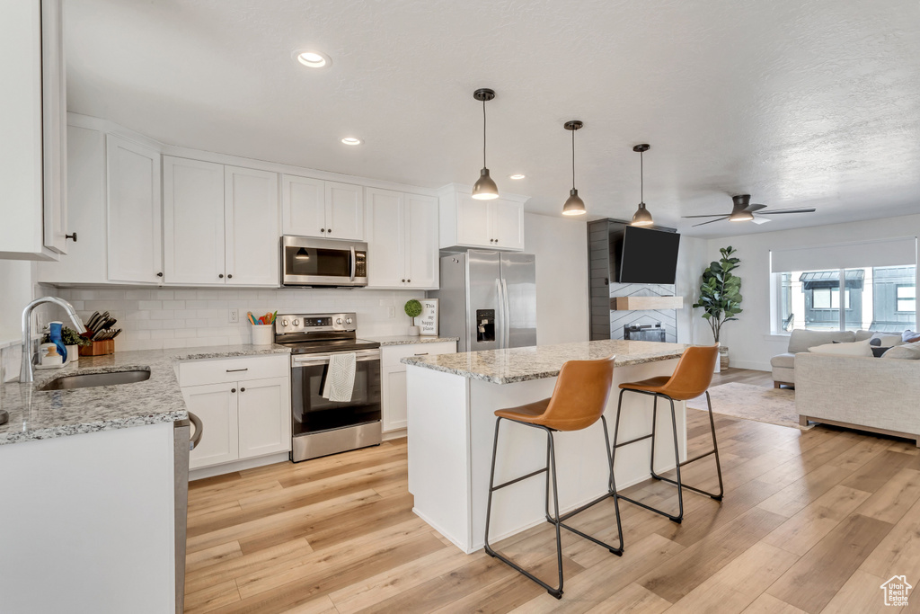 Kitchen featuring sink, white cabinets, appliances with stainless steel finishes, light hardwood / wood-style flooring, and ceiling fan