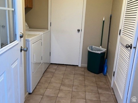 Washroom with independent washer and dryer, light tile flooring, and cabinets