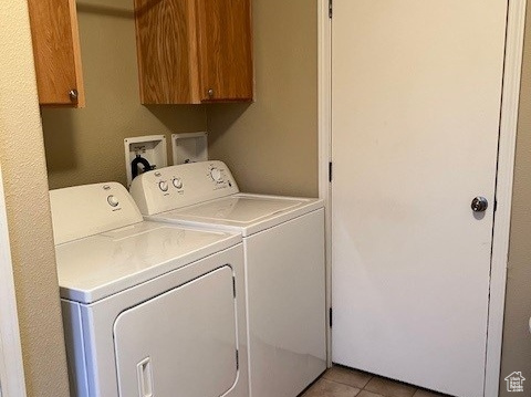 Clothes washing area featuring light tile flooring, washing machine and dryer, cabinets, and hookup for a washing machine