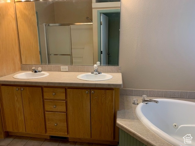 Bathroom featuring tile flooring, a washtub, double sink, and vanity with extensive cabinet space