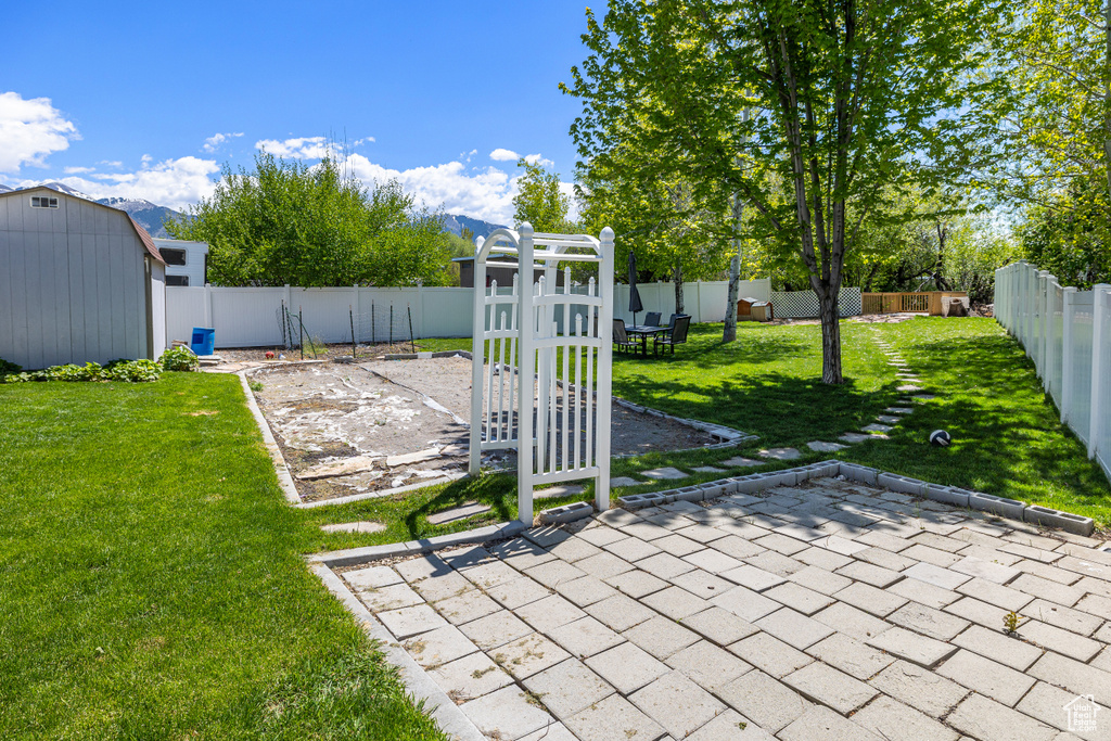 View of yard featuring a patio area, a playground, and a storage shed
