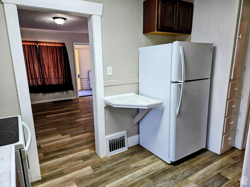 Kitchen featuring dark brown cabinets, dark hardwood / wood-style flooring, white fridge, and range