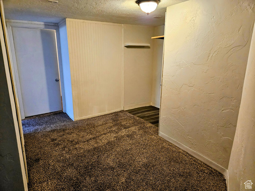 Empty room featuring a textured ceiling and dark carpet