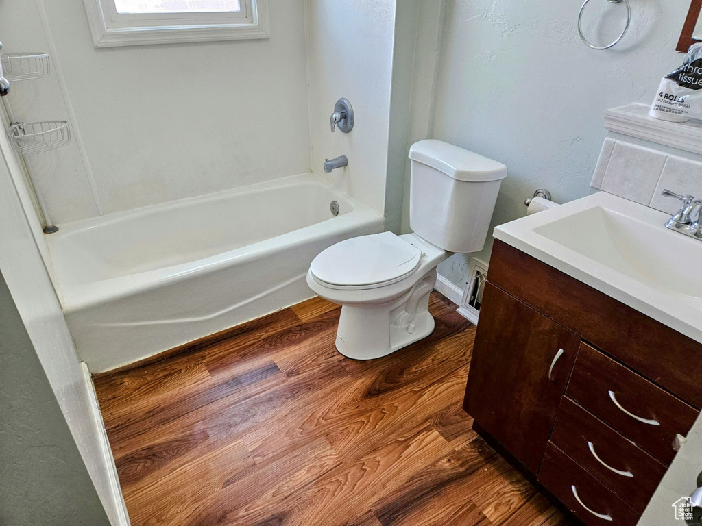 Full bathroom featuring vanity, shower / washtub combination, hardwood / wood-style floors, toilet, and backsplash