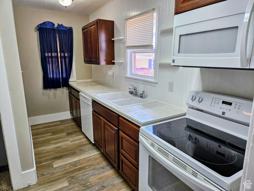 Kitchen featuring white appliances, light hardwood / wood-style flooring, and sink