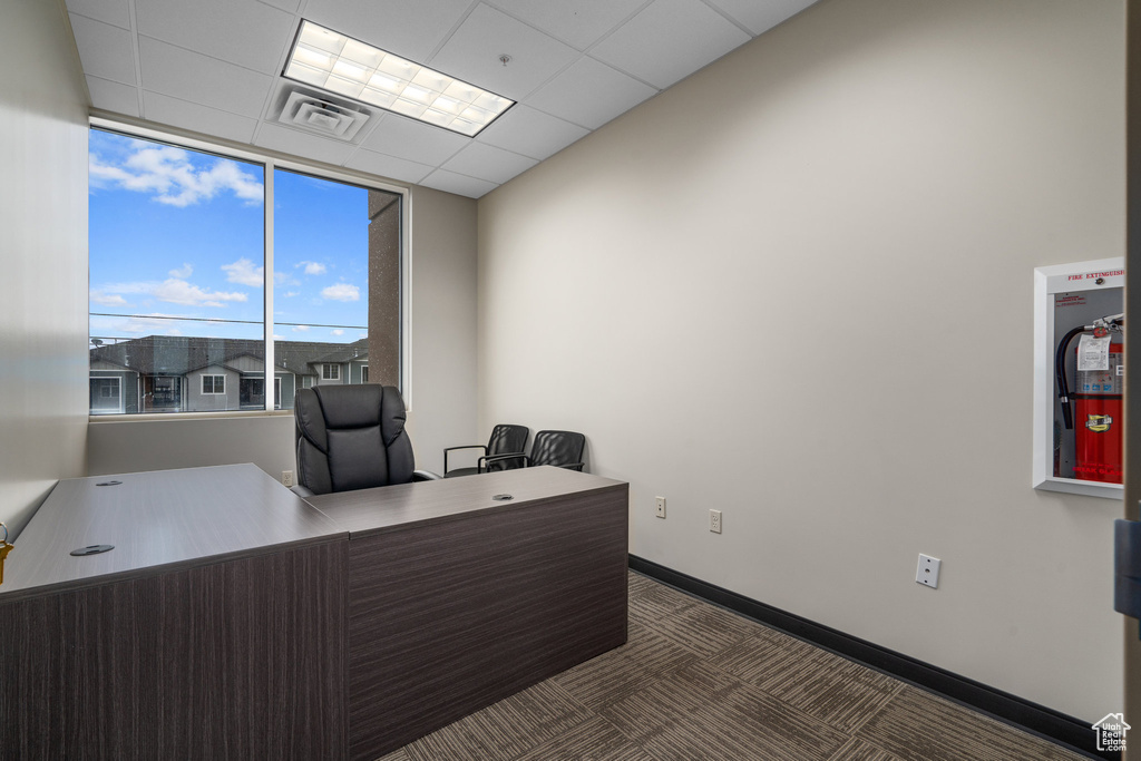 Office area with a paneled ceiling and dark carpet