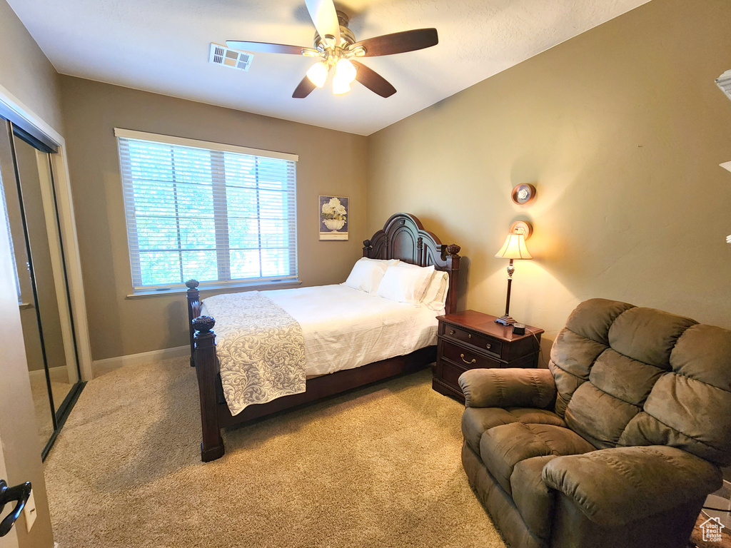 Bedroom with light carpet, a closet, and ceiling fan