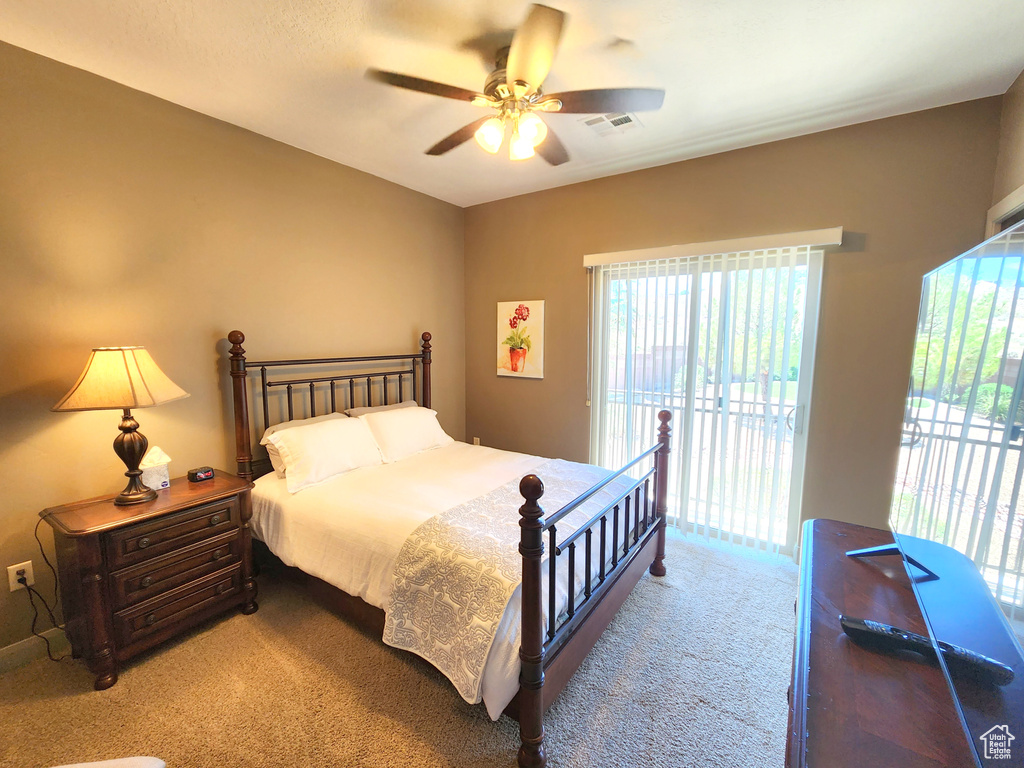 Carpeted bedroom featuring access to exterior, multiple windows, and ceiling fan