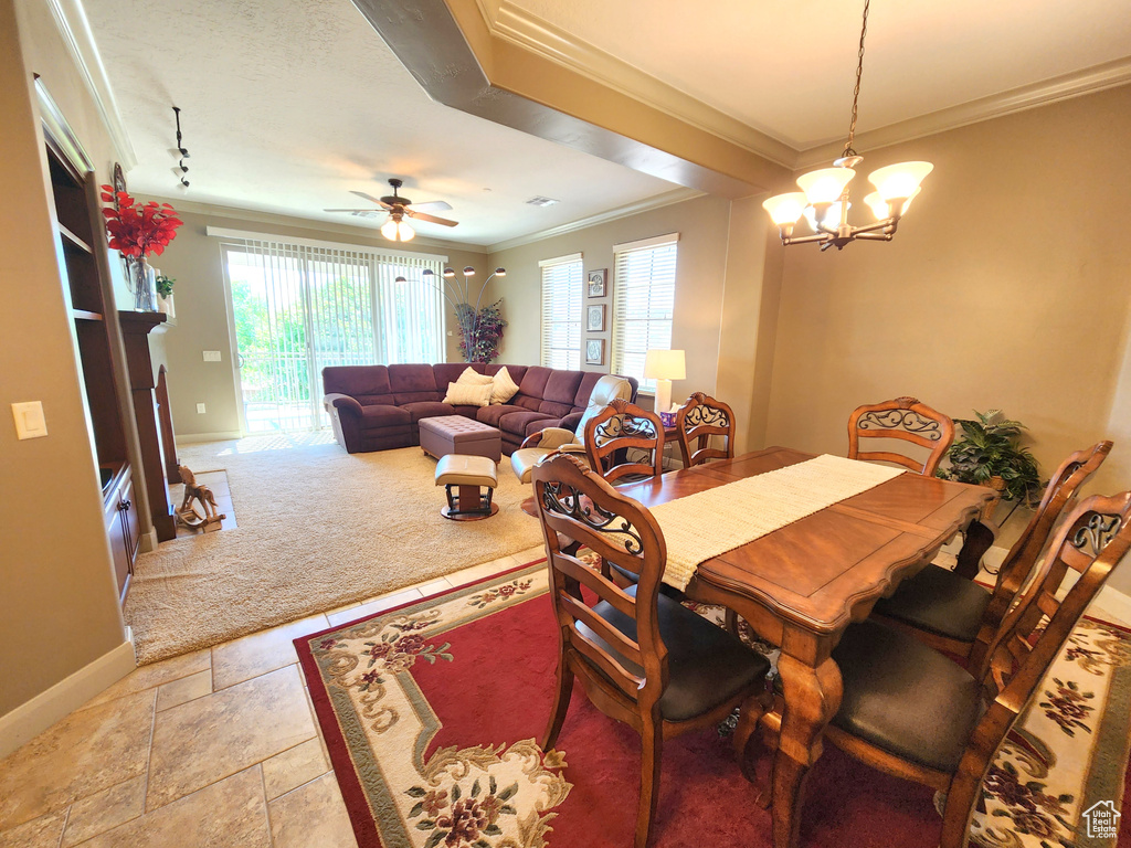 Dining area featuring light tile floors, crown molding, and ceiling fan with notable chandelier