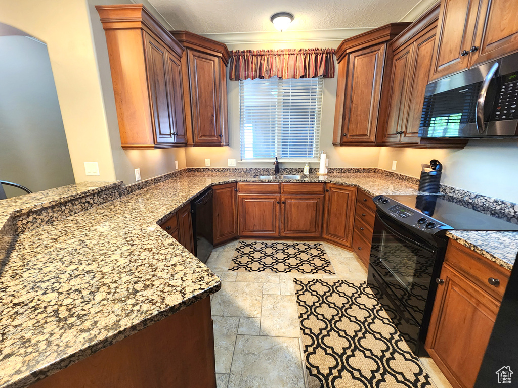 Kitchen featuring light tile floors, light stone counters, sink, and black appliances
