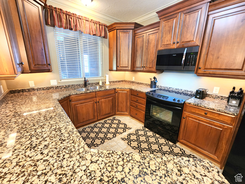 Kitchen with light tile floors, light stone counters, sink, crown molding, and electric range
