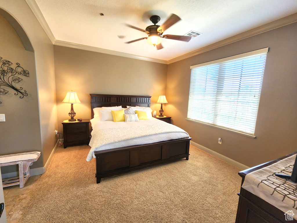 Bedroom with light colored carpet, crown molding, and ceiling fan