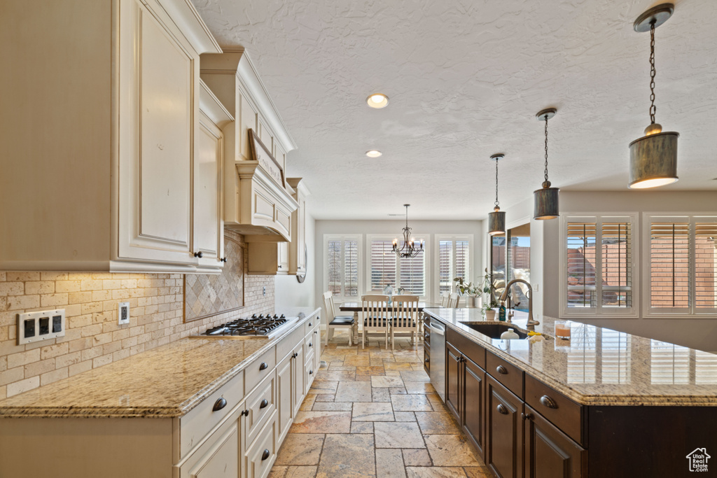 Kitchen featuring tasteful backsplash, sink, dark brown cabinetry, an inviting chandelier, and decorative light fixtures