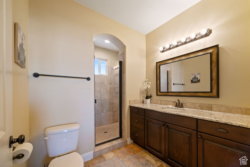 Bathroom featuring tile flooring, a shower with shower door, toilet, and vanity