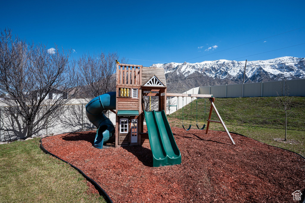View of jungle gym with a mountain view and a lawn
