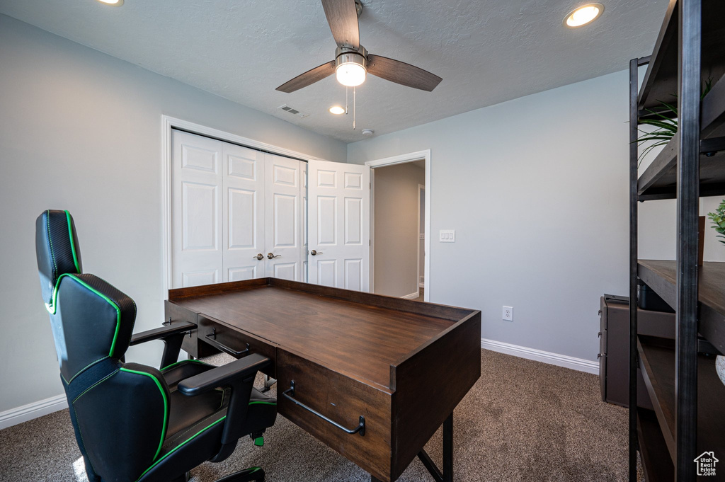 Office area with dark carpet and ceiling fan