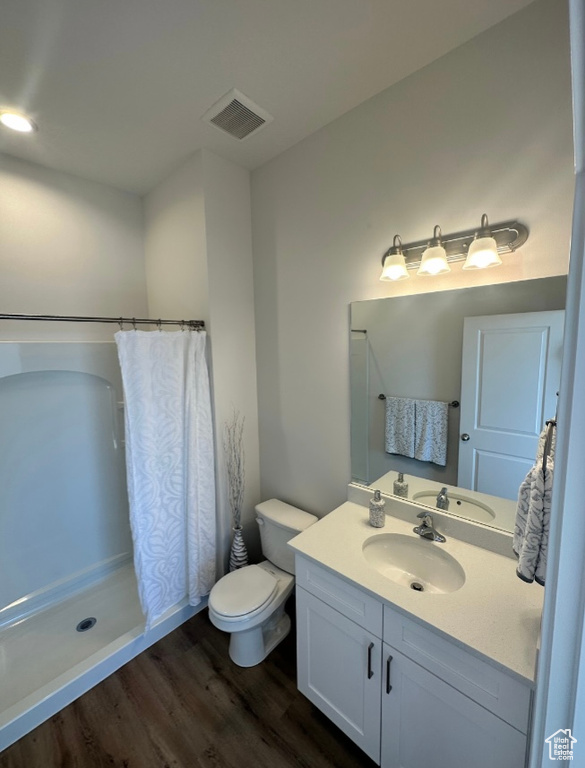 Bathroom with curtained shower, hardwood / wood-style floors, toilet, and vanity