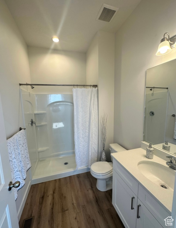 Bathroom featuring hardwood / wood-style floors, toilet, vanity, and a shower with curtain