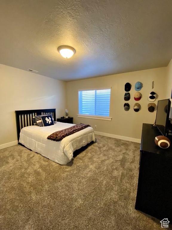 Bedroom with a textured ceiling and dark colored carpet