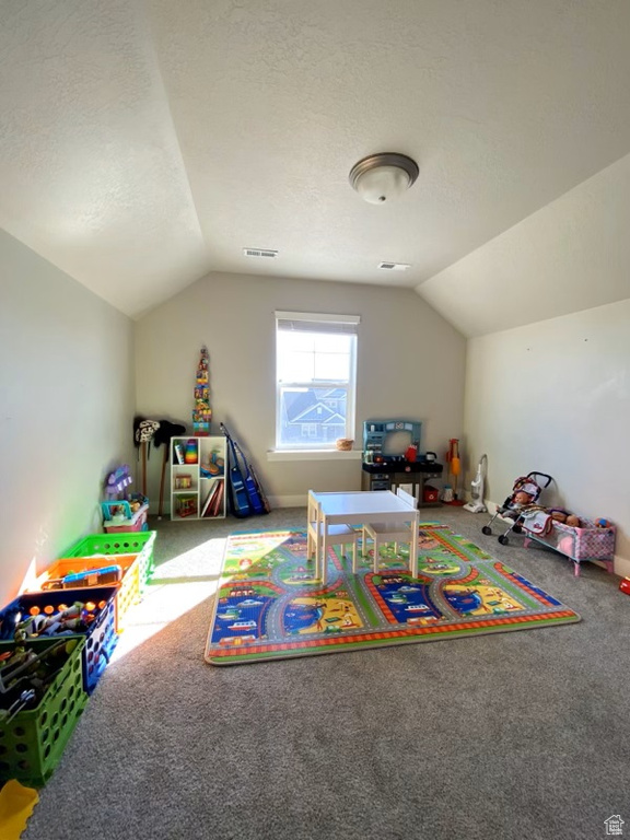 Playroom with light colored carpet, a textured ceiling, and vaulted ceiling