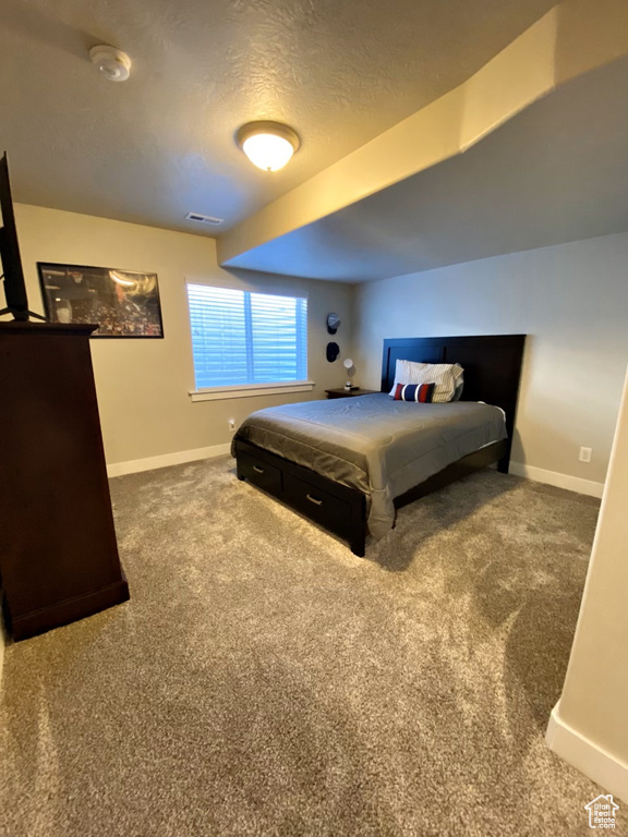 Bedroom featuring dark carpet and a textured ceiling