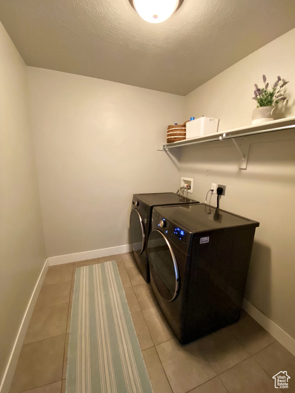Laundry area with washing machine and dryer, hookup for an electric dryer, light tile floors, and washer hookup