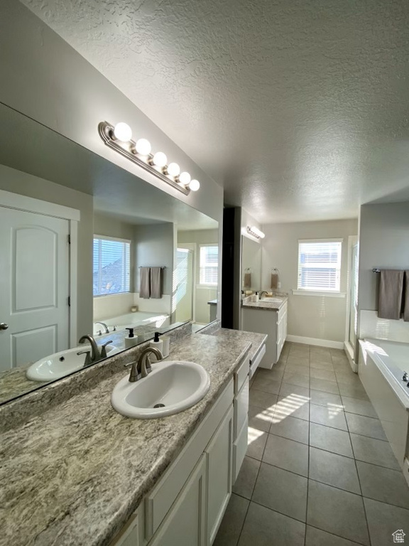 Bathroom featuring vanity, a textured ceiling, a bathing tub, and tile floors