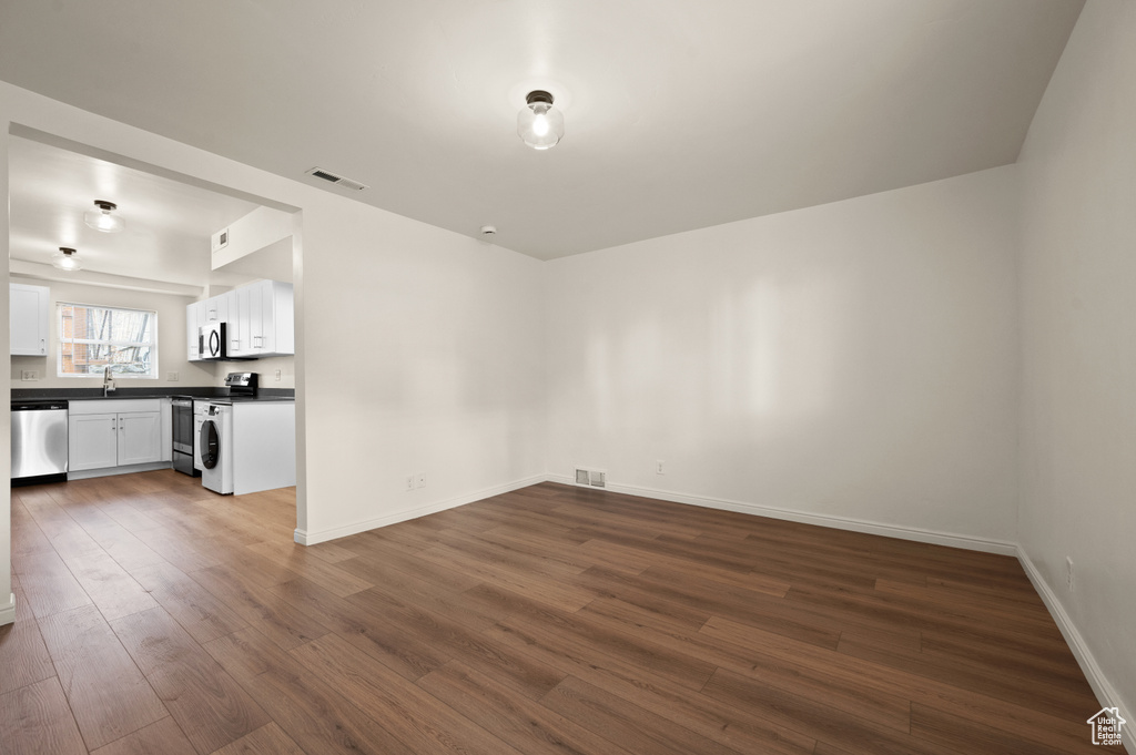 Empty room with dark wood-type flooring and sink