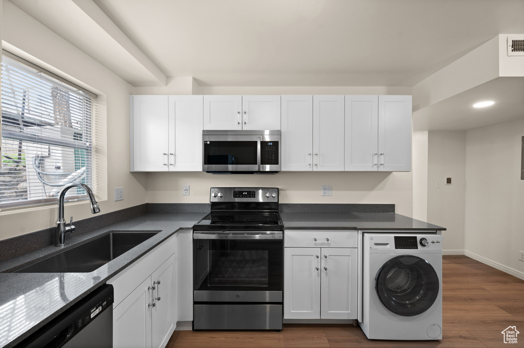 Kitchen featuring white cabinets, stainless steel appliances, dark wood-type flooring, sink, and washer / clothes dryer