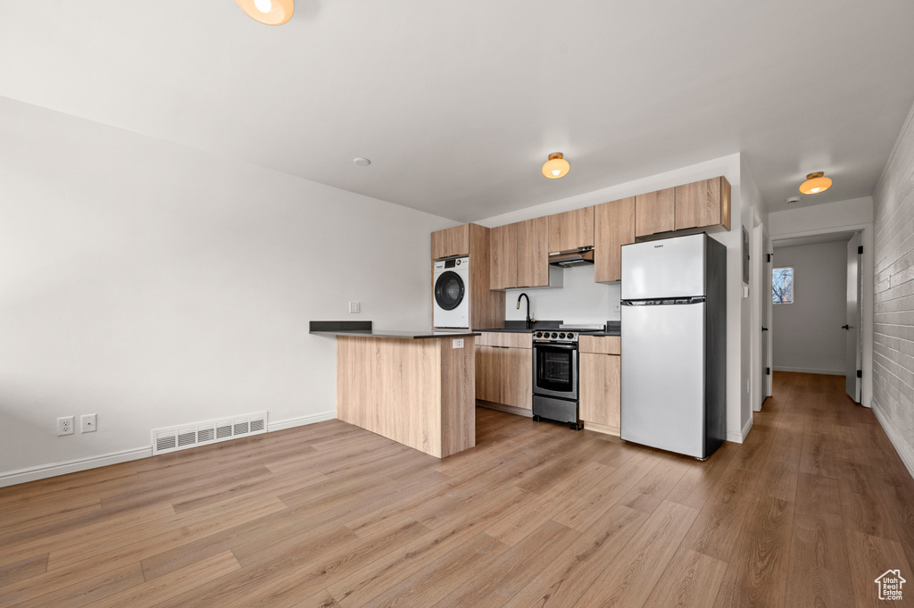 Kitchen featuring sink, stainless steel range oven, light hardwood / wood-style flooring, white refrigerator, and kitchen peninsula