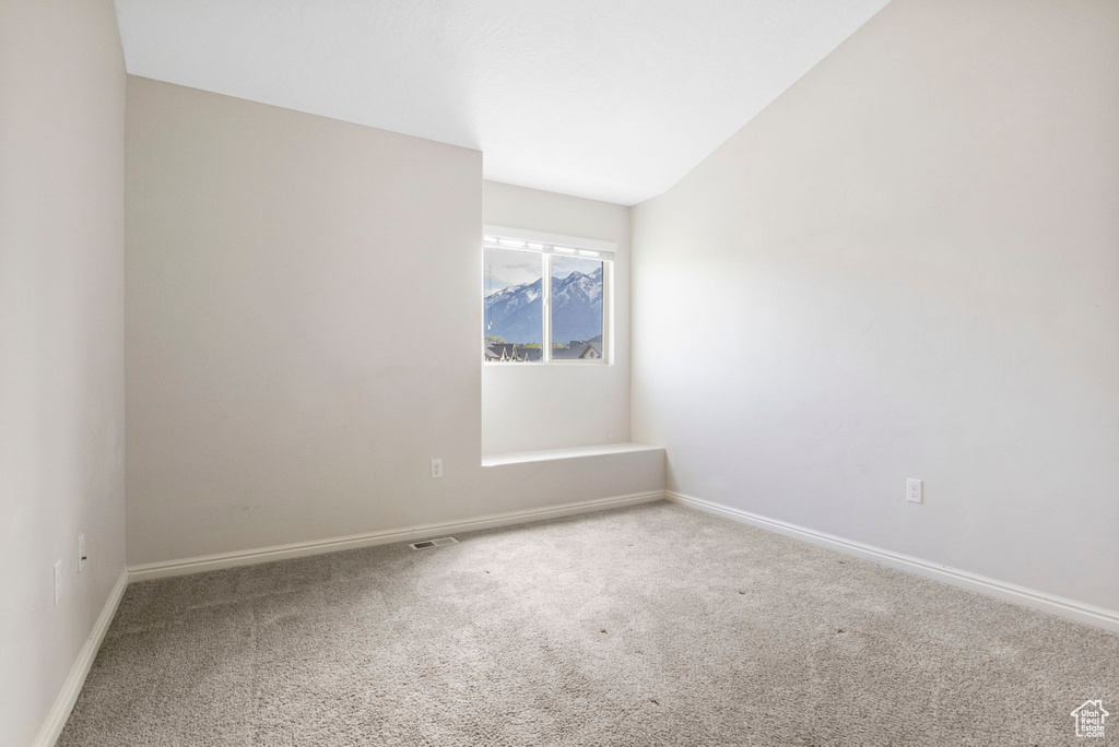 Spare room with vaulted ceiling and carpet flooring