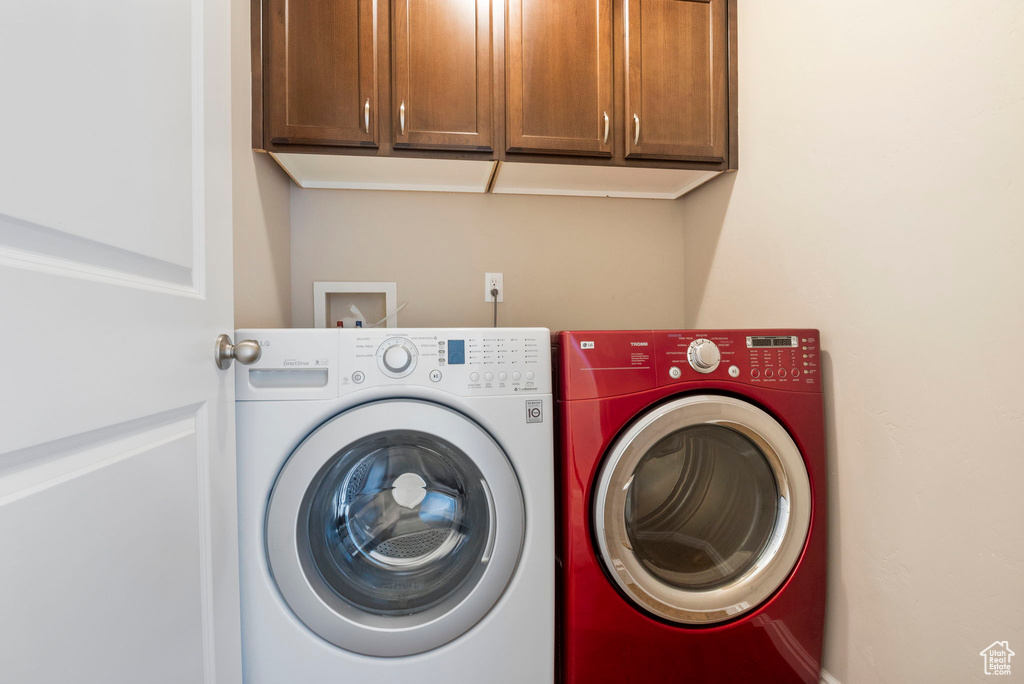 Washroom with cabinets, hookup for a washing machine, and washing machine and clothes dryer